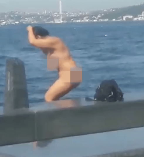 Kimseye aldırış etmeden soyunup denize atladı